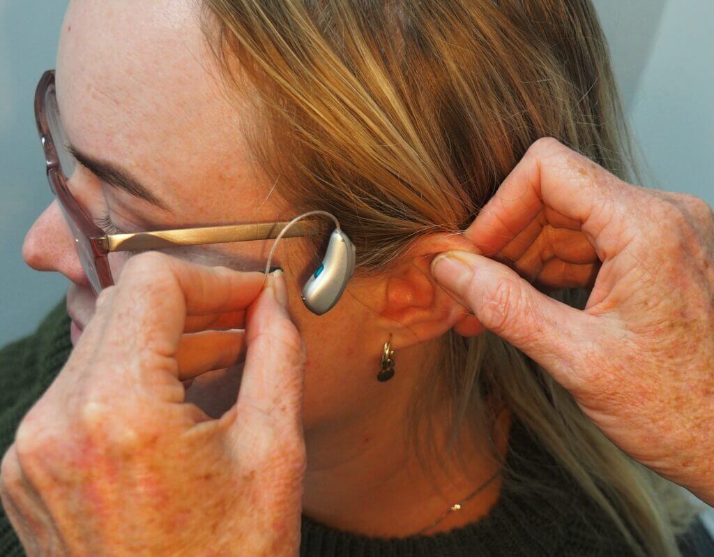 putting a hearing aid on someones ear