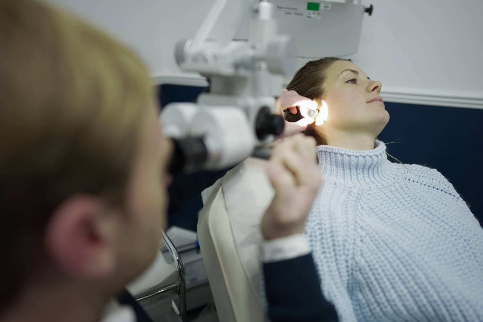 brunette patient having ear inspected with light