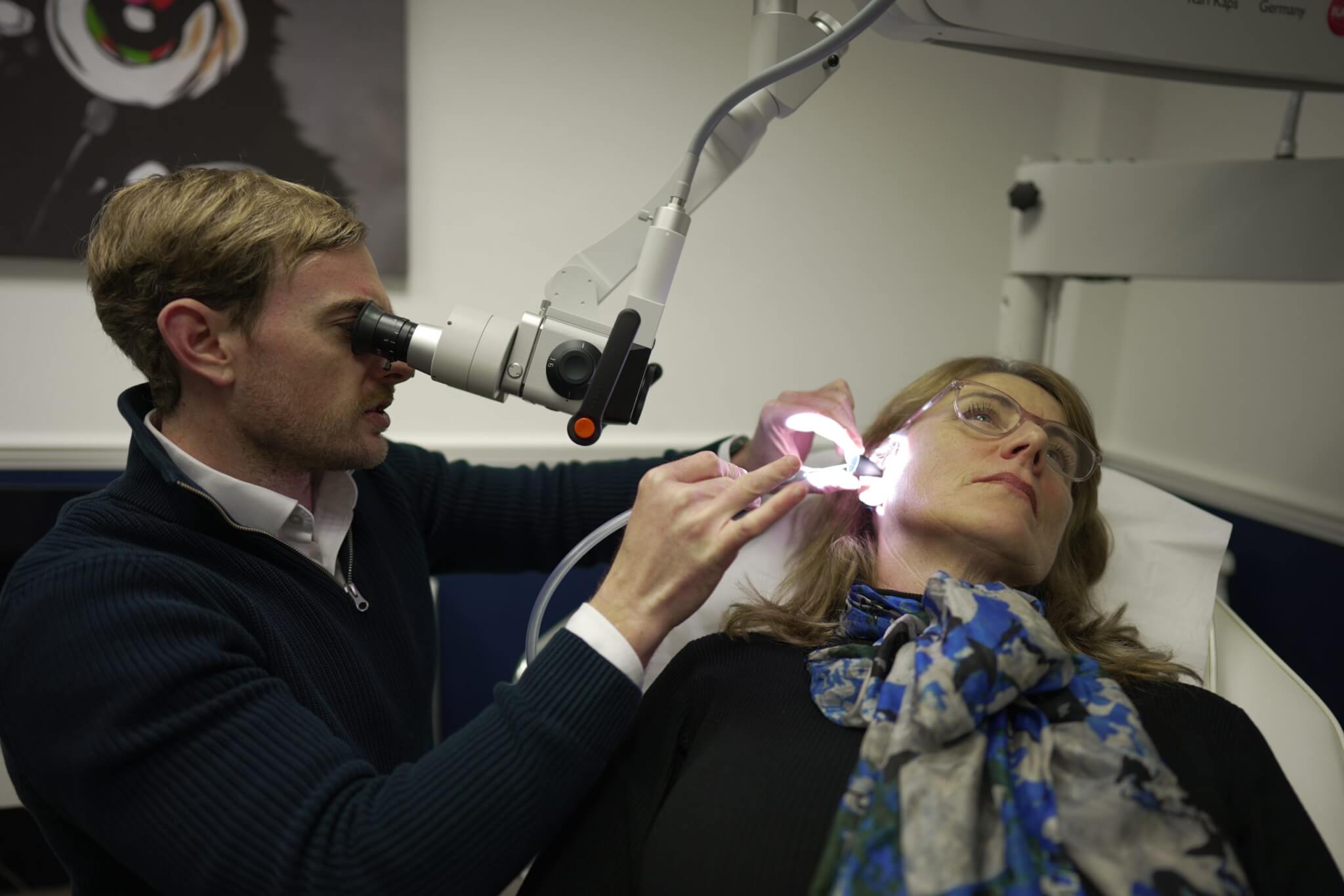 audiologist looking into someones ears in clinic room 2