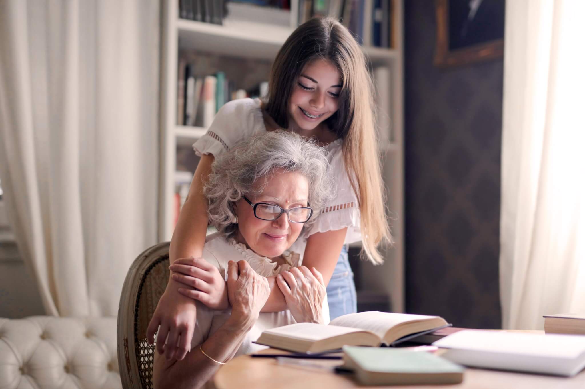 grandma and grand-daughter smiling and reading together